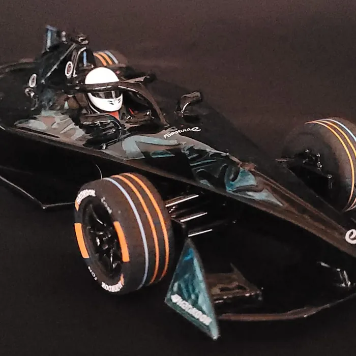 Miniatura de carro de Fórmula E preto com detalhes laranja